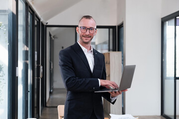 Fototapeta premium businessman handsome smiling using laptop while standing in office