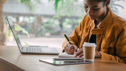 Take notes with a pen. Young african american university foreign exchange students study online on...