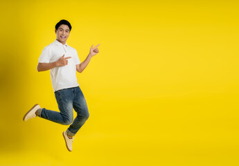 Full length image of young Asian man on yellow background