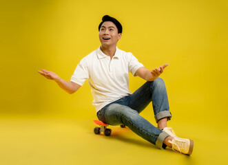 image of young asian male playing skateboard on a yellow background