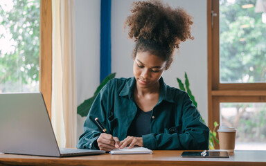 take notes in a notebook, African American housewife looking at family grocery store income and expenditures and calculate household expenses , insurance, water, electricity