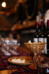 Wine tasting in Armenia. Glass made of woven vine. Many empty glasses and bottle and cheese plate for a snack on the background