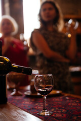 Wine tasting in Armenia. A hand pours wine from a bottle into a glass, people are tourists in the background, gastronomic