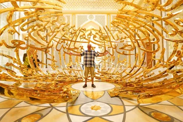 Poster älterer aktiver Mann steht fröhlich im Präsidentenpalast in Abu Dhabi unter vergoldeter Dekoration des Eingangs © globetrotter1