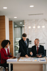 Happy businesspeople while collaborating on a new project in an office. Group of diverse businesspeople using a laptop and tablet in office..