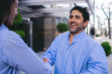 Enthusiastic middle-aged Latin man shaking hands with a prospective client.