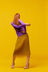 Faceless portrait of slim woman with long straight red hair wearing retro fashion outfit in action...