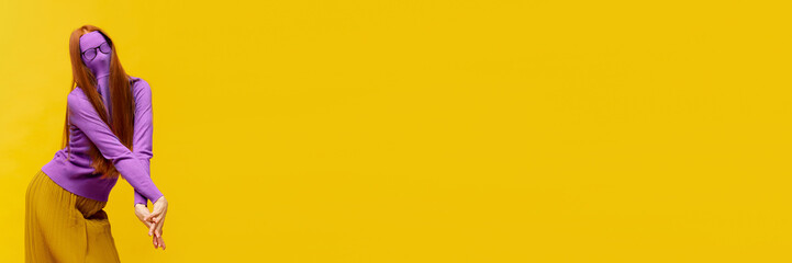 Obraz premium Faceless portrait of slim woman with long straight red hair wearing retro fashion outfit in action over yellow studio background. Impersonal emotions, body language