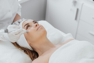 Obraz na płótnie Canvas Radiofrequency facial skin lifting. Hardware cosmetology RF lifting procedure and hardware facial massage. Rejuvenation, skin care in a beauty salon. Woman doctor cosmetologist and girl in spa clinic.