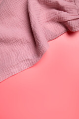 Texture of pink muslin fabric on pink background. Cotton textile and clothing. Soft delicate natural organic cotton fabric for sewing, needlework, baby towel, diaper, dress. Fabric background