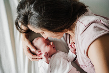 elevated view of mother hugging cute newborn baby girl yawning at home. Family concept