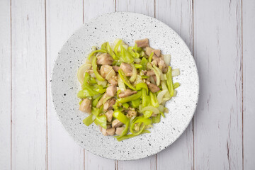 Top view of Stir fried green pepper with chicken in white dish on wooden table.