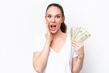 Young caucasian woman taking a lot of money isolated on white background with surprise and shocked facial expression