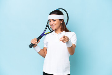 Young tennis player woman isolated on blue background pointing front with happy expression