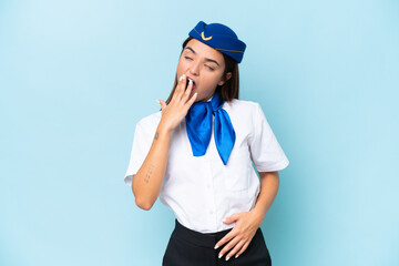 Airplane stewardess caucasian woman isolated on blue background yawning and covering wide open mouth with hand