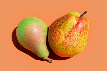 Ripe pears. Two juicy pears on orange background. Ripe fruits close up