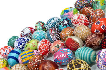 Lots of colorful Easter eggs laid out randomly on a solid white background.