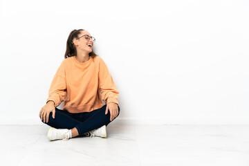 Young woman sitting on the floor laughing in lateral position