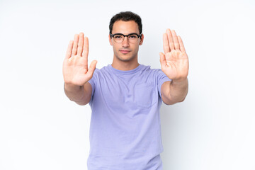 Young caucasian man isolated on white background making stop gesture and disappointed