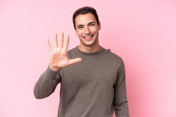 Young caucasian man isolated on pink background counting five with fingers