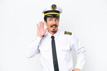 Airplane caucasian pilot isolated on white background listening to something by putting hand on the ear