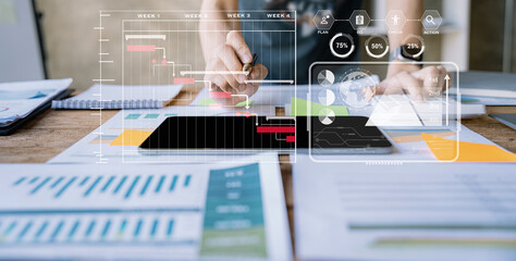 Business woman hand Project manager working and update tasks and Gantt chart scheduling virtual diagram.with smart phone, tablet and laptop in office.