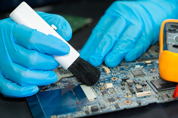 Asian technician repair and cleaning dirty micro circuit main board of smartphone electronic...