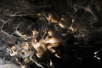 Black gold abstract ocean background. Splashes and waves of sparkling paint under water, clouds of interstellar smoke in motion
