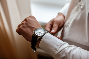 A man in a white shirt wears an expensive watch on his hand.