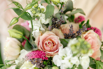 Close-up wedding bouquet with two golden rings lying on a blossoming pink rose bud