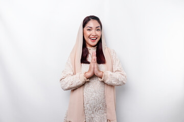 Portrait of a young beautiful Asian Muslim woman wearing a headscarf gesturing Eid Mubarak greeting