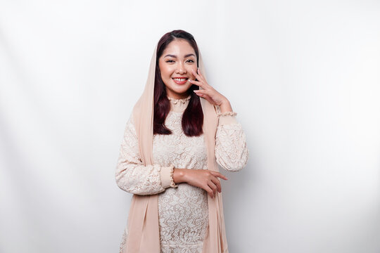Young Asian Muslim woman wearing headscarf smiling to the camera, isolated by white background