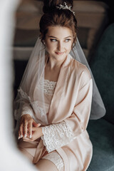 tender morning of the wedding day. fashion photo of beautiful bride with dark hair in elegant wedding dress and diadem posing in room in the wedding morning