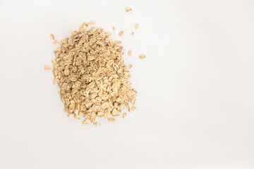Pile of oat flakes on white background. Super food rich in nutrients and that can be used for several recipes. Healthy eating. Top view and copy space.