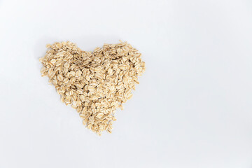 Oat flakes forming a heart on white background, conceptual image. Super food rich in nutrients and that can be used for several recipes. Healthy eating. Top view and copy space
