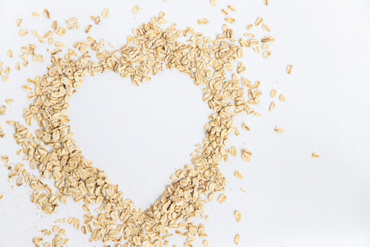 Oat flakes forming a heart shape on white background, conceptual image of good food for health. Super food rich in nutrients and that can be used for several recipes. Top view and copy space