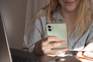 Woman hands holding plastic credit card and using laptop. Online shopping or payment concept. Toned picture. High quality photo. 