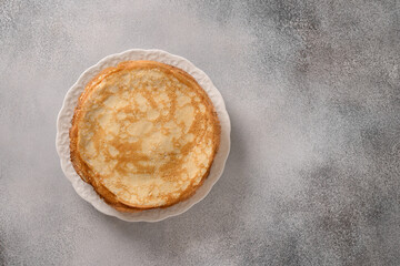 Thin pancakes or russian blini on gray stone background. Top view. Copy space.
