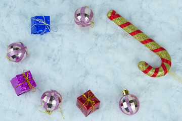Glittered baubles, candy cane with colorful presents with metallic strings.