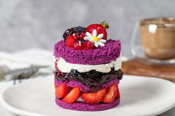 Layered fruit cake. Cake with strawberries, raspberry sauce and cream on a stone background. Patisserie desserts. Close up