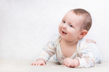 Kid with a smile on a white background. An adorable six month old baby boy is lying on the bed....