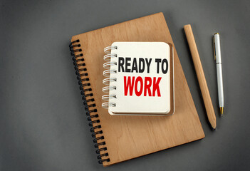 READY TO WORK text on notebook with pen and pencil on grey background