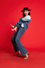 Extravagant cowboy dance. Portrait of beautiful young woman in jeans clothes and black hat posing...