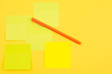 Stickers on a yellow background and a pen as a concept reminder of office work