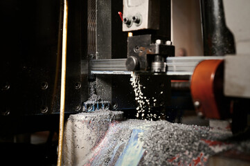 Cutting metal workpiece with band saw in workshop closeup