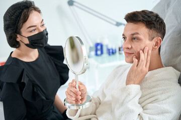 Handsome male looking in mirror in the beauty salon