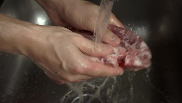 chef man hands wash red meat steak in the sink for grill stuttering