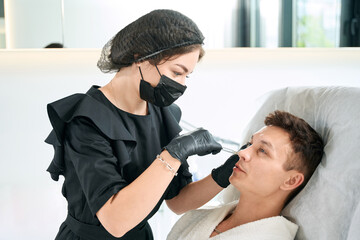 Fototapeta premium Man getting face anti age injection in clinic
