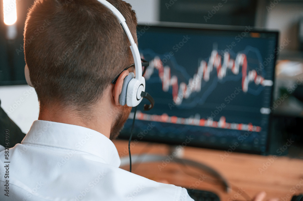 Poster stock exchange graphs on the screen. man in formal clothes is working in the modern office. using co