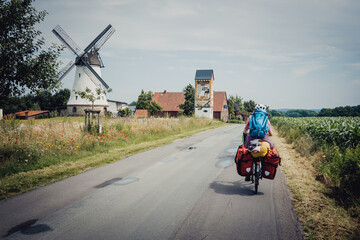 Frau passiert während einer Fahrradtour eine alte Windmühle, Niedersachsen, Deutschland